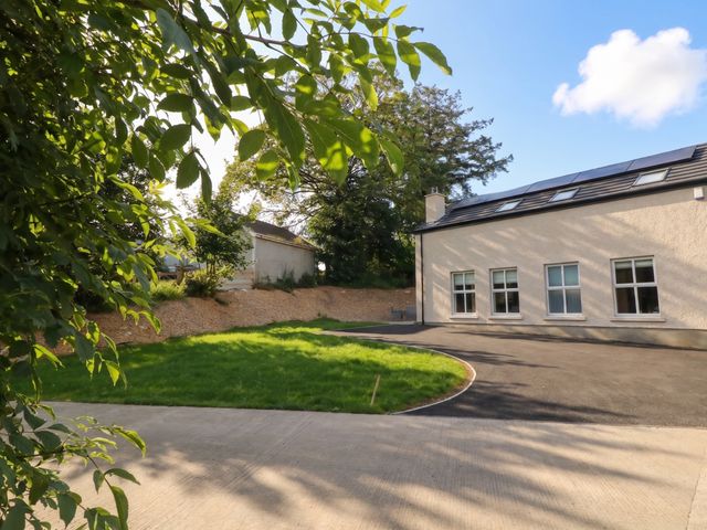 A house with a grassy area and driveway at Brook Cottage in Moneydig near Coleraine