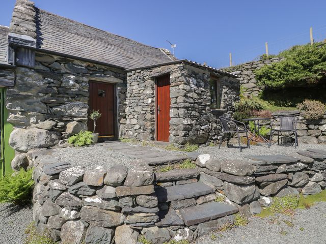 An exterior view of a stone cottage with a table and chairs at Beudy Bach Llanbedr