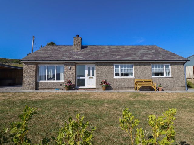 A bungalow with a garden and bench at Tyn Y Weirglodd Deiniolen