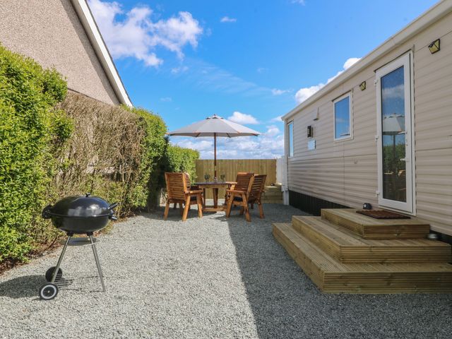An outdoor area with a table and chairs under an umbrella at Temperance Caravan in Trefor