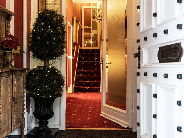 An entrance hall with a staircase and potted plants at Lonsdale House Bowness-On-Windermere