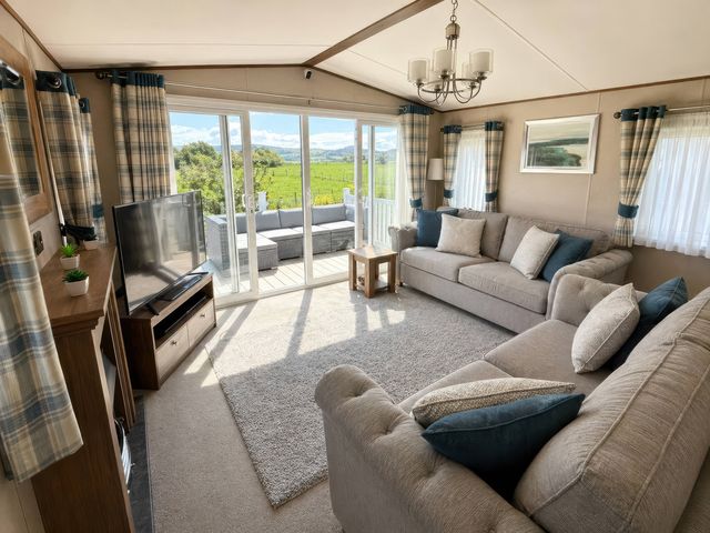 A living room with a sofa and television at Caravan i35 in Conwy