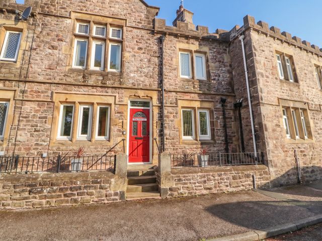 A stone house exterior with a red front door at The Haven in Heysham
