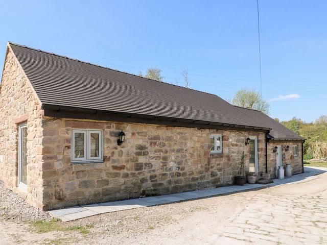A stone cottage with windows and a door at Churn Dash Cottage in Derby