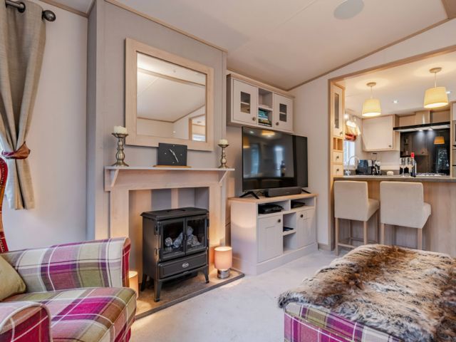 A living room with a fireplace and television at Four Seasons in Holt
