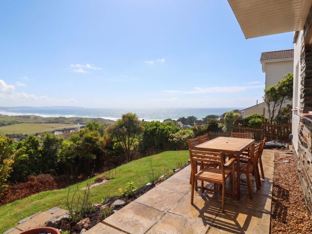 A garden with a dining table and chairs overlooking the ocean at Belvedere in Woolacombe