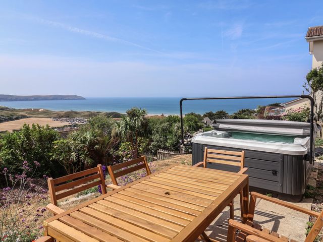 An outdoor area with a hot tub and dining table overlooking the ocean at Belvedere in Woolacombe