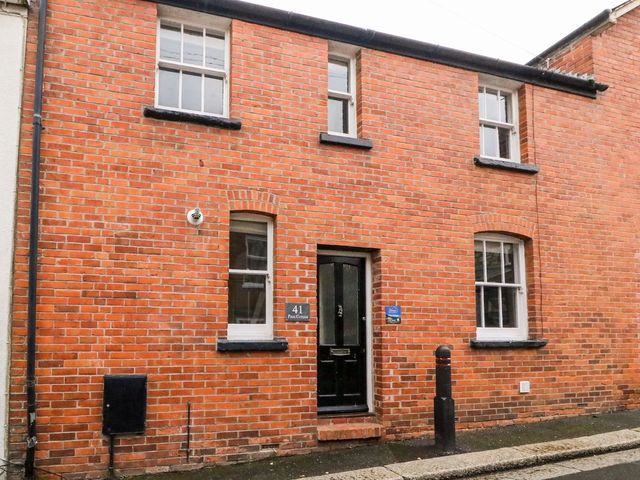 A house exterior with brick wall and front door at Pixie Cottage in Weymouth