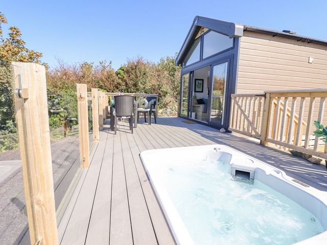 An outdoor area with a hot tub and seating at Posh Pod in Cemaes Bay