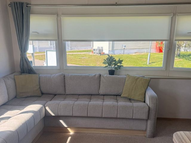 A living room with a sofa and a plant at Caravan - Sleeps 6 - Parking in Lossiemouth