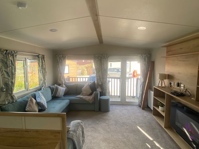 A living room with a sofa and television at Coworth Deluxe Cabin with Garden