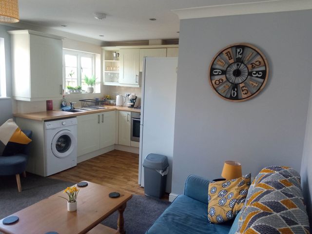 A kitchen with a washing machine and a clock at Ground Floor Cornish Retreat Free Parking in Bodmin