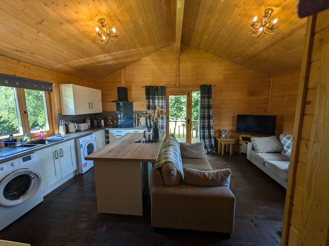 A kitchen with a washing machine and sofa at Pet Friendly - Lodge at Riverview Holiday Park Mangerton near Newcastleton