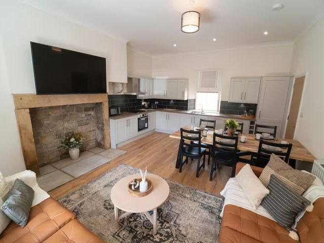 A living room and kitchen area with a television and dining table at Foundry Farm Apartment
