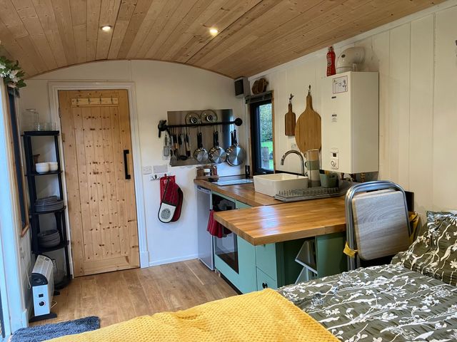 A kitchen with a sink, stove, and refrigerator at Transformed Railway Wagon- Sleeps2-Garden-Firepit in Powys near Crickhowell