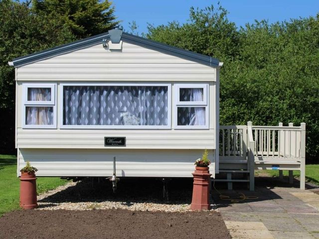 A mobile home with a deck and planters at 84 Sandhills in Ingoldmells