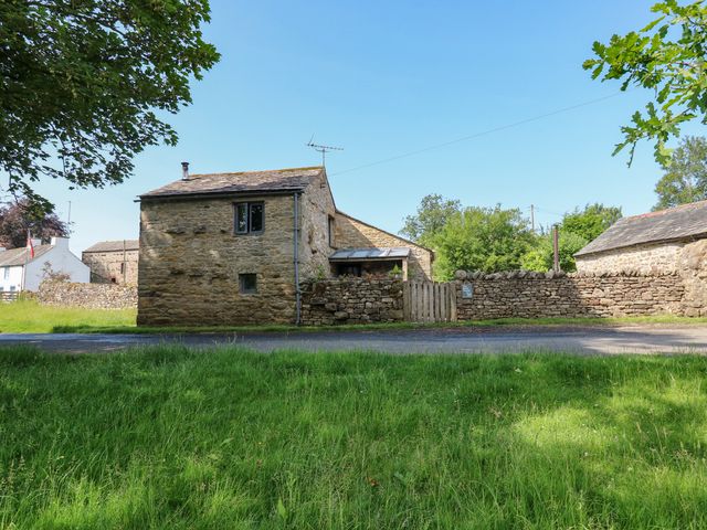 A stone house with a fence and grass at The Brew House in Penrith
