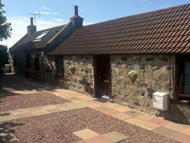 An outdoor area with a stone wall and door at Viola Cottage St Combs near Fraserburgh