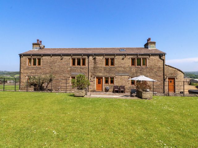 An outdoor view of a stone house with a patio at Sheephouse Farm in Bacup