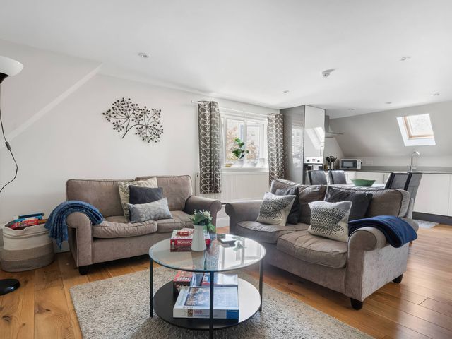 A living room with sofas, a coffee table and kitchen units at TBC in 