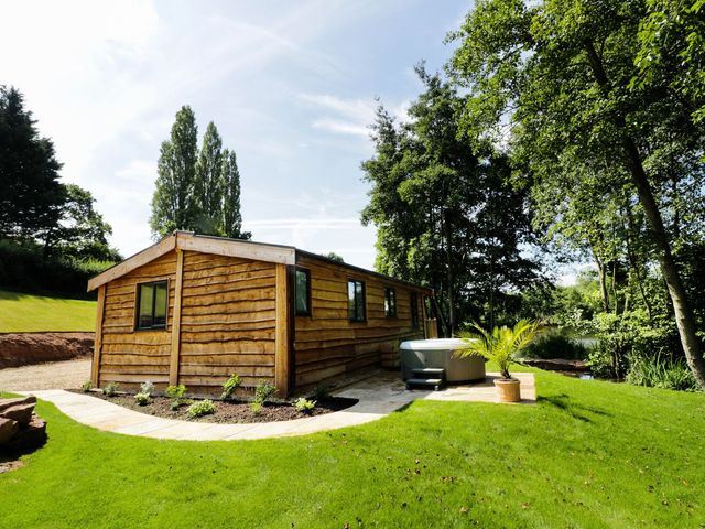 A wooden cabin with a hot tub in an outdoor area at Kingfisher in Ross-on-Wye