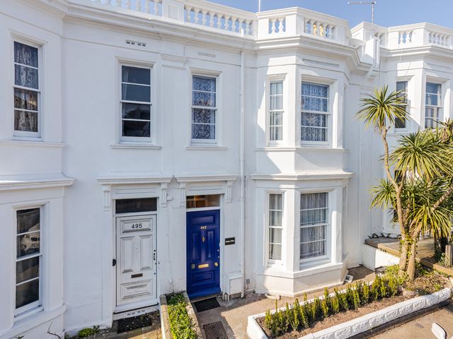 An exterior view of a white building with blue door and windows at Palm Villa in Torquay