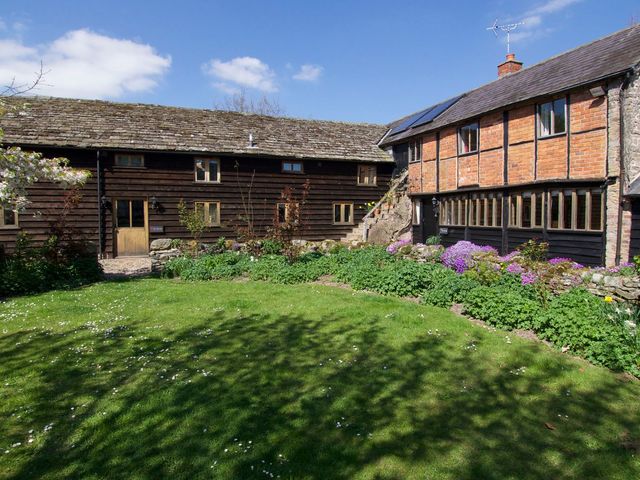 A garden with buildings and grass at The Old Barn in Hereford