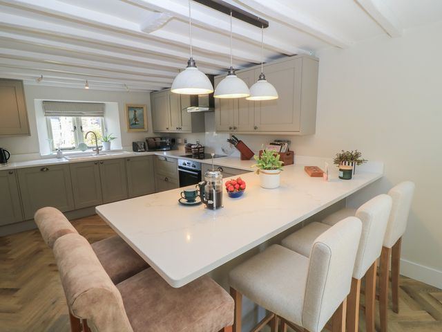 A kitchen with a countertop and bar stools at 2 The Gardens in Lechlade