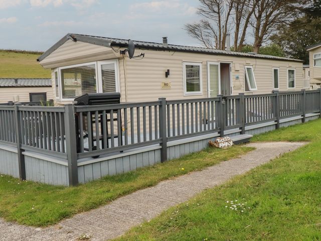 A caravan with decking and a fence at Tucked Away in Newquay