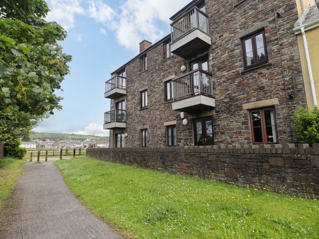 An apartment building with balconies and a stone wall at Twyni Bach
