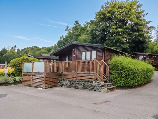 A wooden lodge with a deck and surrounding trees at 89 Ambleside in White Cross Bay