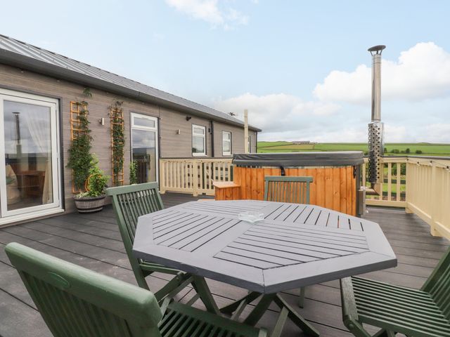 An outdoor deck with a table and chairs and a hot tub at The View in Ilkley