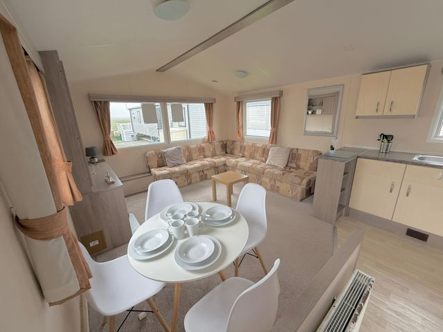 A living room with a sofa and dining area at Holiday Park Seawick in Clacton-on-Sea