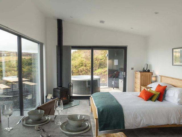 A bedroom with a bed and a dining set at Migdale Heights - Luxury Cabins in The Highlands