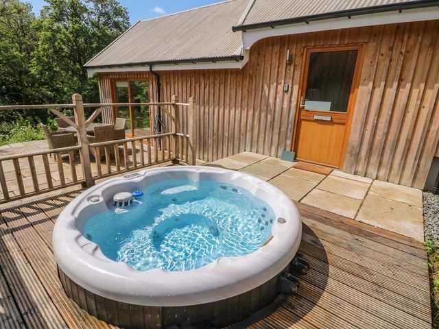 A hot tub on a deck with chairs and a door at Yew Tree in Killin