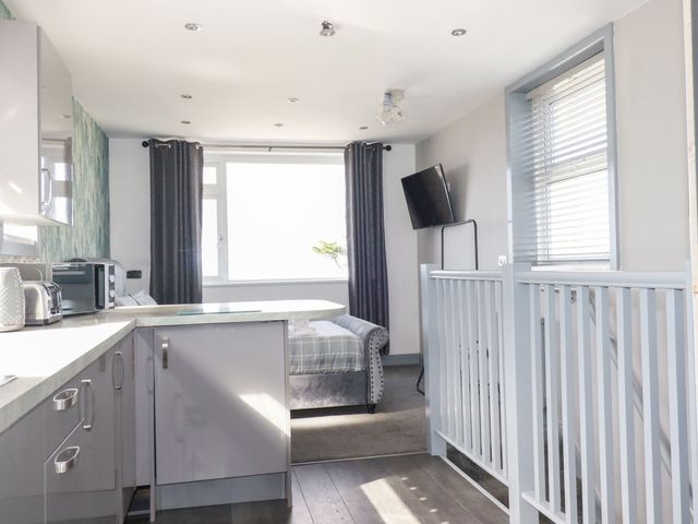 A kitchen with a sofa and television at Penthouse No.3 in Newquay