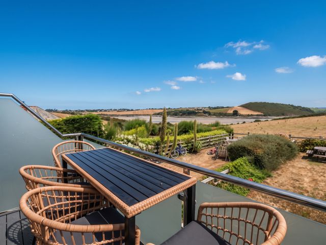 An outdoor seating area with a table and chairs overlooking a landscape at Little House in Wadebridge