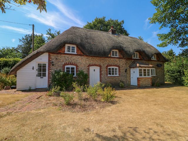A thatched roof cottage with a garden area at Little Owl High Cross near Petersfield