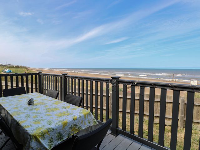 A deck with a table and chairs overlooking the ocean at Plot 34 in Bacton