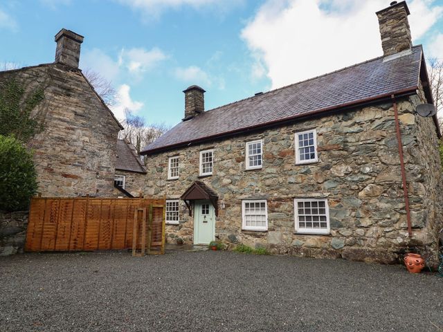 An outdoor view of a stone house with a wooden fence at Cader Cottage Dolgellau