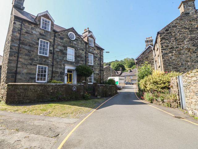 A building with a stone wall and flowers on the side at Tan y Gader in Dolgellau
