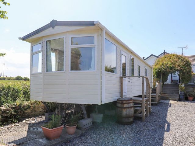 A mobile home with stairs and potted plants at The Lodge in Amlwch