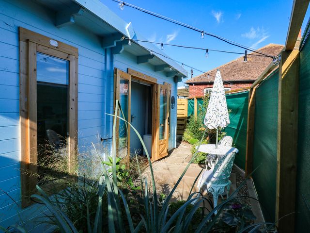 An outdoor area with a blue building, table and chairs at The Cabin in Herne Bay