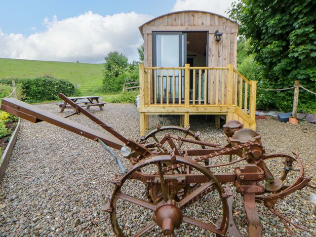 A wooden hut with a deck and old farming equipment at The Hut in Llandysul