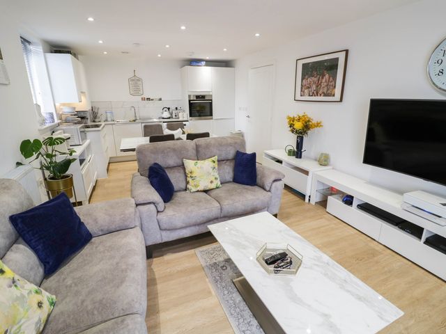 A living room with a sofa, coffee table, and television at 4 Goldcrest Close in Daventry