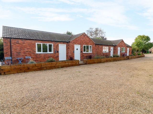 A brick building with multiple units and a gravel driveway at Walcott Lodges - Catley in Billinghay, Lincolnshire
