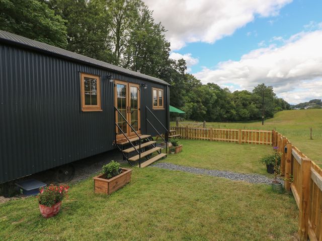 A shepherd's hut with wooden steps and planters at Cwtch Y Bugail 2 Near Llandeilo