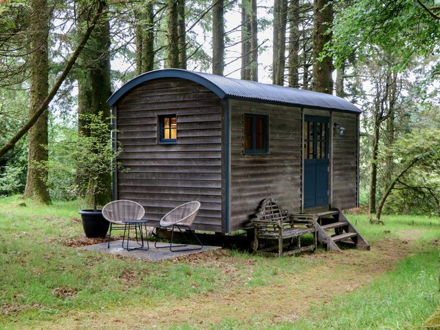 A view of a shepherds hut with chairs and a planter at Ridden Brake shepherds hut in Yelverton