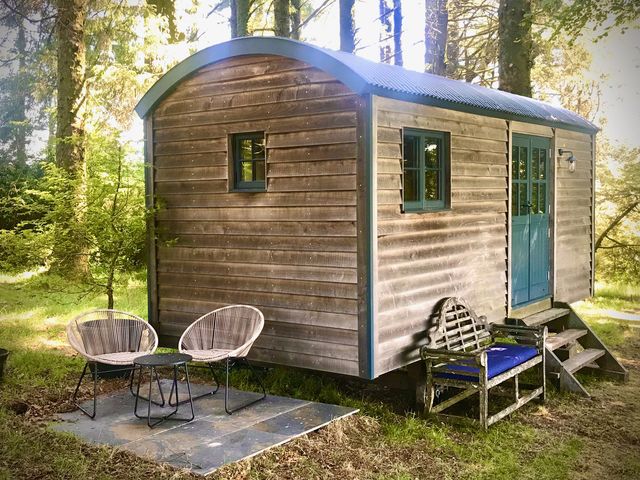 A wooden cabin with a blue door and outdoor seating at Goldcrest in Postbridge