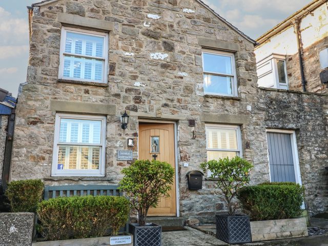 A house front view with stone walls and a door at Dibble Cottage in Reeth